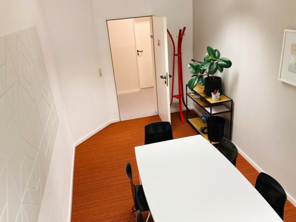 Modern eingerichteter Meetingraum für 6 Personen mit großem Tisch und bequemen Stühlen.